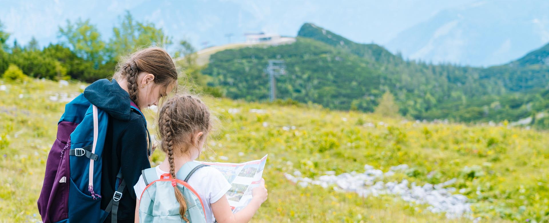 Kinder wandern an einem schönen Sommertag in den Alpen Österreich ruht auf Felsen. Kinder schauen sich die Berggipfel im Tal an. Aktiver Familienurlaub mit Kindern.Outdoor Spaß und gesunde Aktivität
