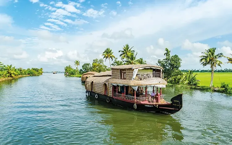 Traditionelles Hausboot fährt auf einem ruhigen Fluss, umgeben von Palmen und grüner Landschaft