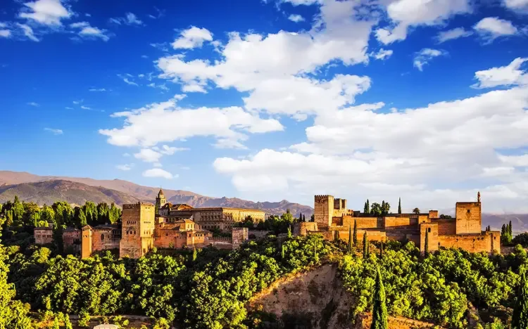 Blick auf die Alhambra von Granada mit grüner Landschaft und Bergen
