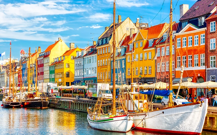 Bunte Häuserfassaden und Segelboote am Nyhavn-Kanal in Kopenhagen bei sonnigem Wetter.