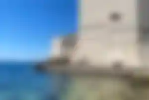 Stadtmauer von Dubrovnik am Adriatischen Meer Massive Stadtmauer von Dubrovnik direkt am Meer mit klarem Wasser und historischem Bauwerk