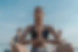Person in Meditationshaltung während einer Yoga-Klasse am Strand