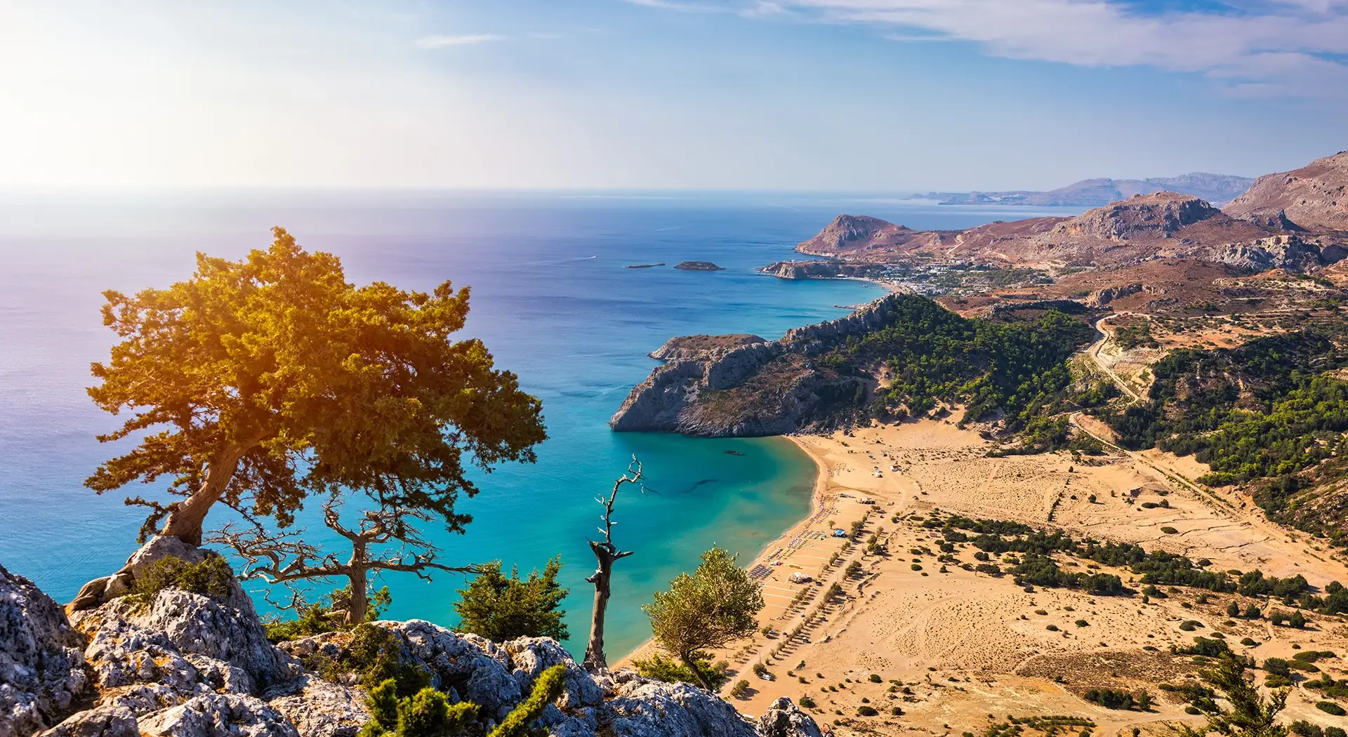Türkisfarbene Badebucht mit kristallklarem Wasser, Ausflugsboot und bewaldeter Felsenküste auf Rhodos