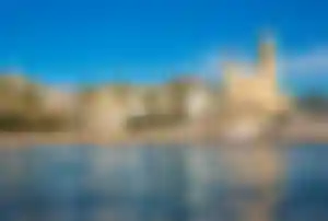 Blick auf die Küste von Sitges mit Kirche, Yachthafen und Palmenpromenade am Mittelmeer