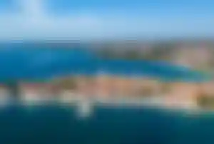 Luftaufnahme der Altstadt von Poreč mit Hafen, Booten und dicht bebauten Häusern, umgeben vom Meer und der Küstenlandschaft der istrischen Region.