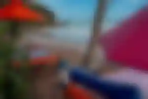 Strandliegen mit bunten Auflagen und Sonnenschirmen an einem tropischen Strand in Sri Lanka