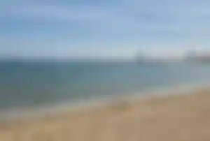 Strand in Barcelona mit Blick auf das Meer Sandstrand in Barcelona mit Blick auf das Meer, sanfte Wellen und das W Hotel in der Ferne unter blauem Himmel mit Wolkenstreifen