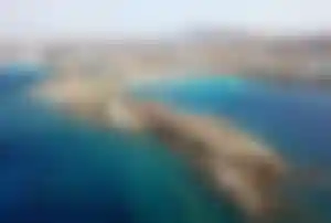 Sandstrand und türkisblaues Meer am Paraga Beach auf Mykonos mit felsiger Küstenlandschaft