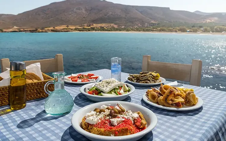 Traditionelle griechische Gerichte und Ouzo auf einem Tisch mit Meerblick.