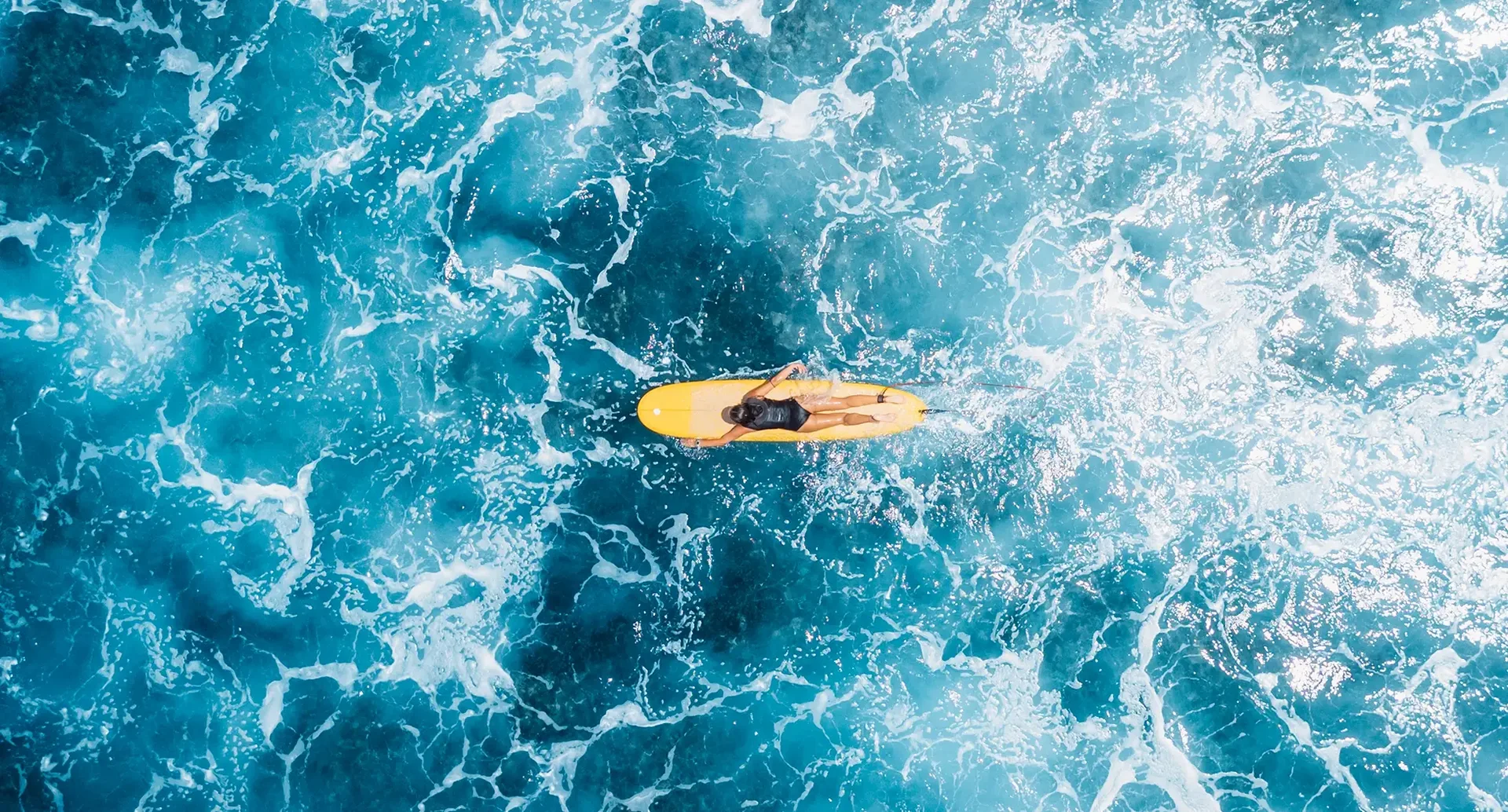 Surferin paddelt über türkisblaues Wasser
