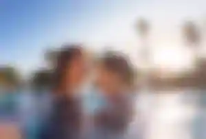 Erwachsene Person und Kind im Pool einer Hotelanlage in Antalya, umgeben von Palmen bei warmem Sonnenlicht.