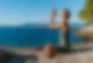 Person sitzt in Yoga-Position auf Felsen am Meer mit Blick auf das Wasser und die Küstenlandschaft