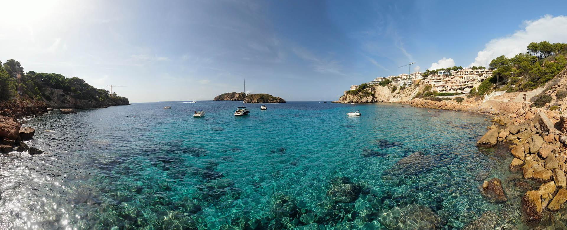 Türkisblaues Meer mit Booten in einer mediterranen Bucht – ideales Reiseziel zum Urlaub buchen im Reisebüro Reisewelt