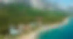 Luftaufnahme der Küste von Antalya mit türkisfarbenem Meer, grünen Hügeln, Stränden und Hotelanlagen entlang der Bucht.