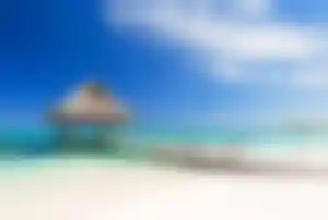 Steg mit Strohhütte am weißen Sandstrand in der Dominikanischen Republik – tropisches Reiseziel im Winter
