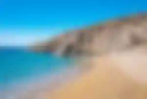 Ruhiger Sandstrand von Agrari Beach auf Mykonos mit felsiger Küste und klarem Meerwasser
