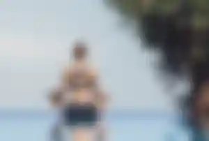 Person meditiert in Lotushaltung am Infinity-Pool mit Blick auf das Meer