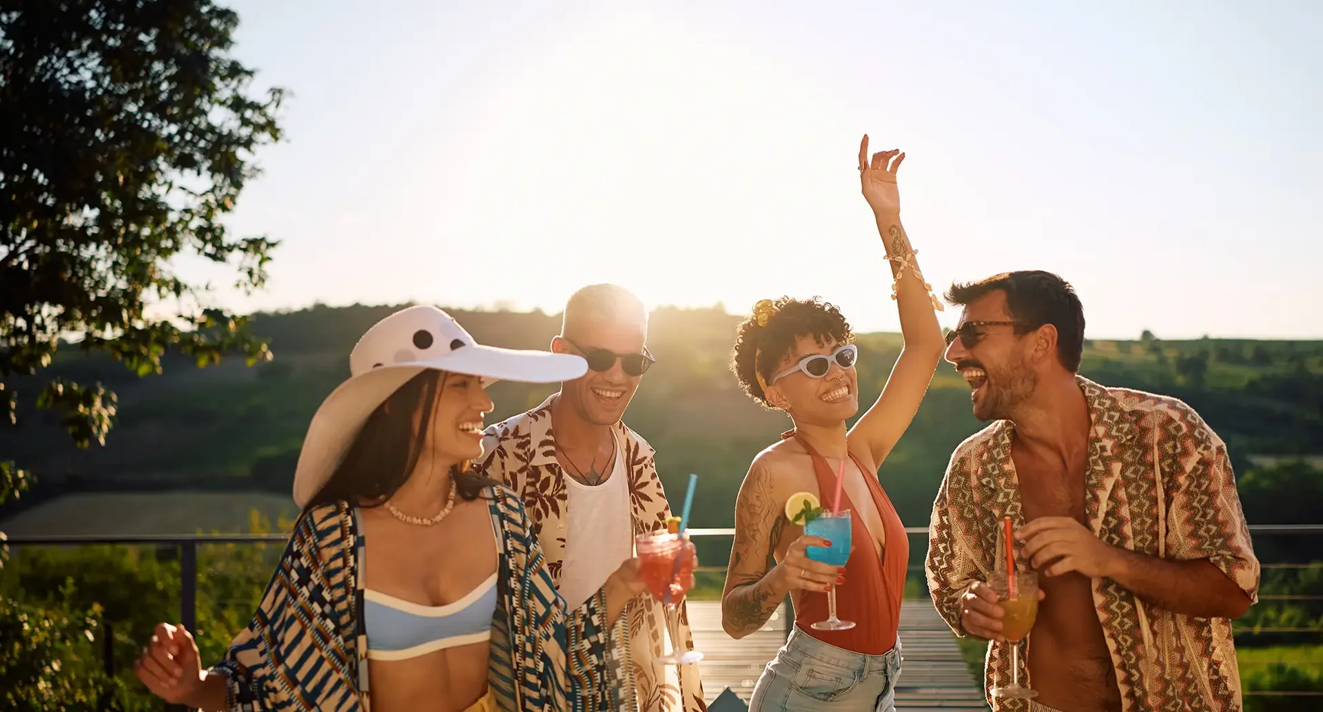 Gruppe junger Reisender feiert im Partyurlaub im Freien mit Cocktails, Musik und sommerlicher Atmosphäre