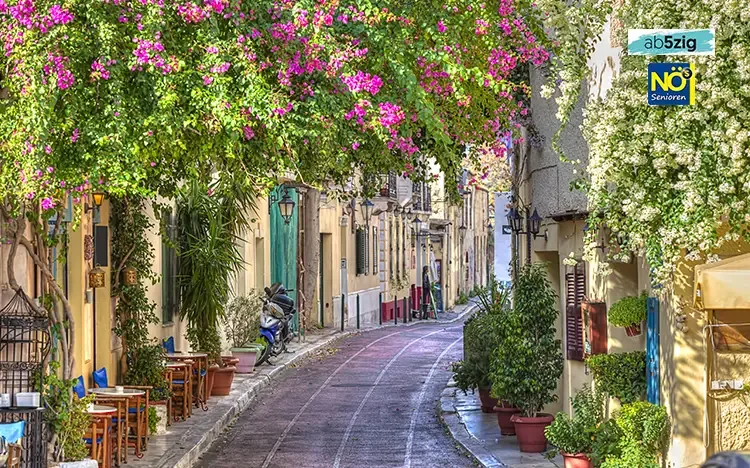 Malerische Gasse im Stadtteil Plaka in Athen mit blühenden Pflanzen und Cafés
