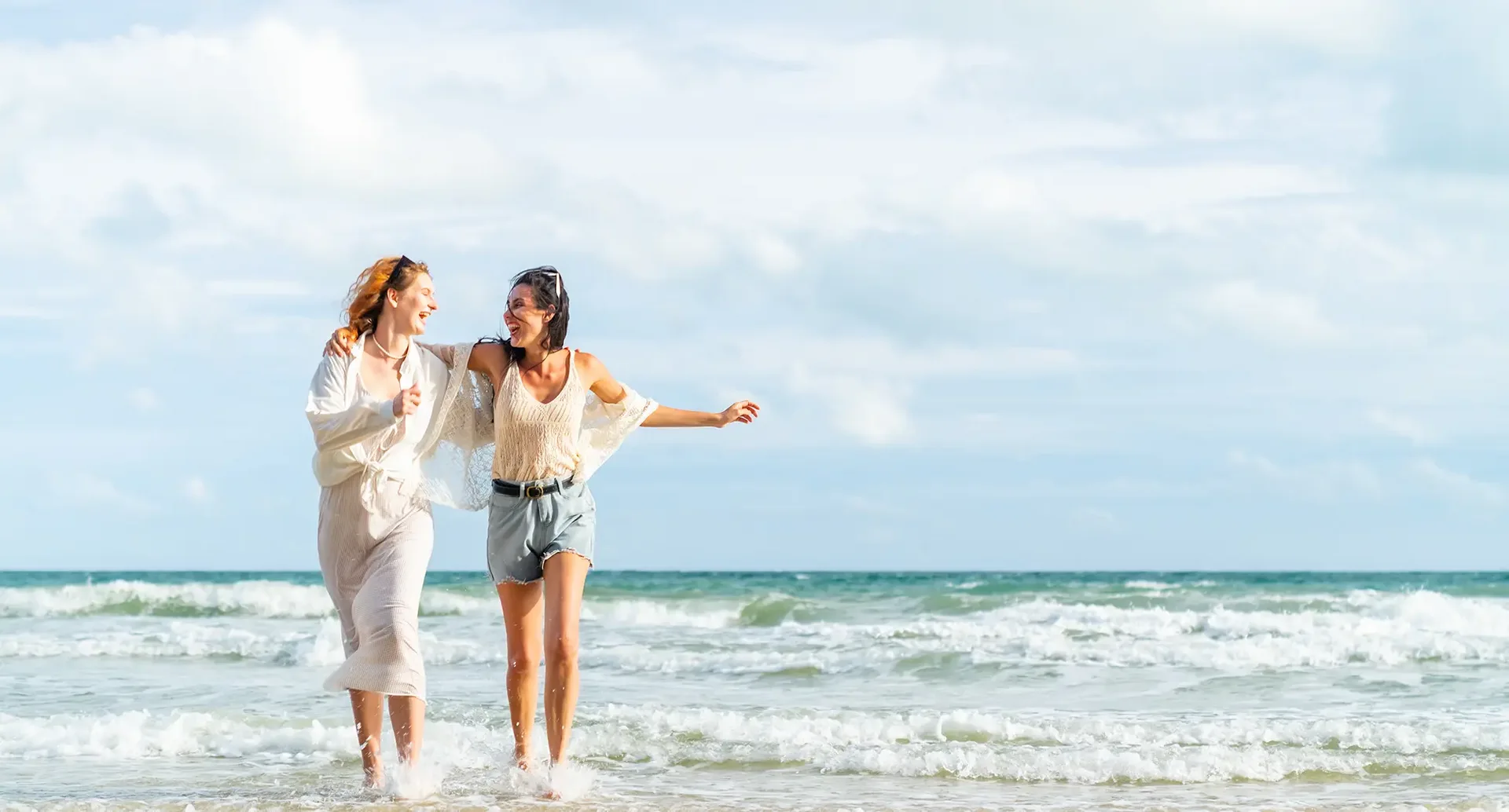 Zwei Personen laufen gemeinsam durch das Meer an einem Sandstrand und genießen den Urlaub auf Mykonos