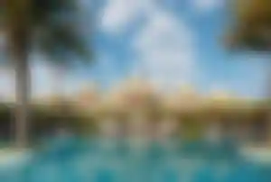 Außenansicht des Raffles The Palm Dubai mit großzügiger Poolanlage, Palmen und luxuriösem Strandresort auf der Palm Jumeirah