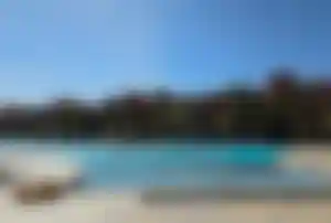 Hotelpool mit Palmen und rötlicher Hotel im Hintergrund in Ägypten, Hurghada