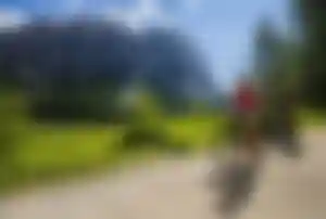 Aktivurlaub im Herbst: Mountainbiken in den Dolomiten Zwei Personen beim Mountainbiken in den Dolomiten auf einem Bergweg mit beeindruckender Felskulisse und grüner Natur – ideal für Outdoor-Aktivitäten im Herbst