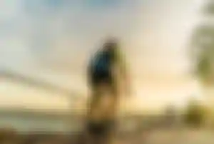 Person fährt mit einem Fahrrad auf einer Promenade entlang der Küste bei Sonnenuntergang mit Blick auf das Meer