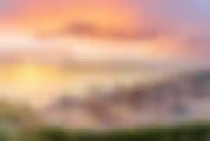 Strand am Roten Meer mit Sonnenschirmen und Steg bei Sonnenuntergang in Ägypten