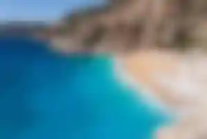 Sandstrand am Kaputaş Beach mit kristallklarem türkisfarbenem Wasser und steilen Felsklippen an der türkischen Mittelmeerküste.
