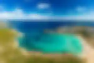 Türkisfarbene Bucht auf Menorca mit feinem Sandstrand und kristallklarem Wasser im Mittelmeer