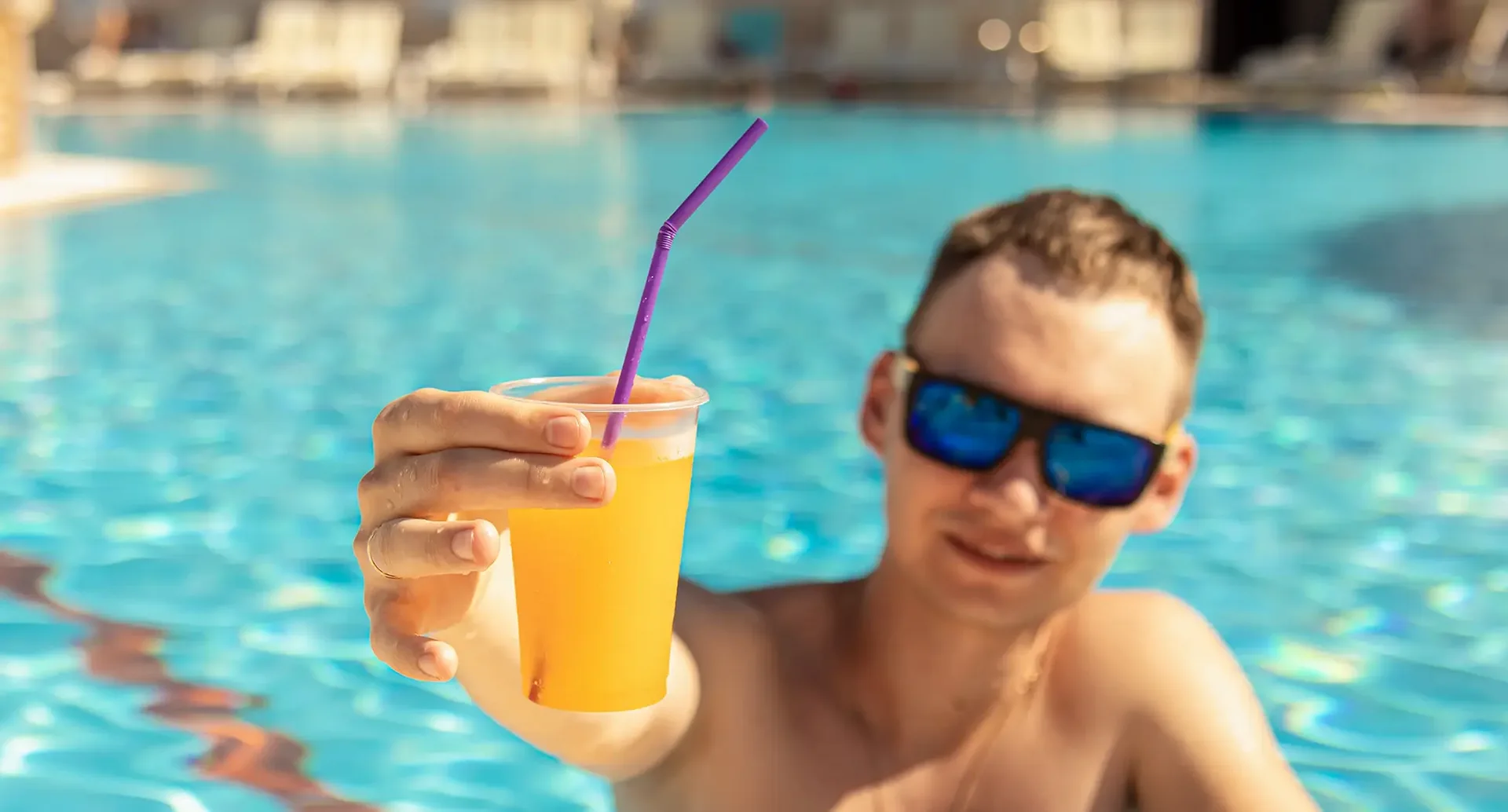 Mann im Pool zeigt Orangensaft