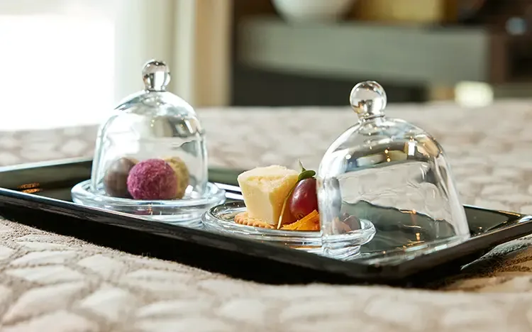 Gourmetpralinen und Snacks unter Glasglocken auf einem Serviertablett