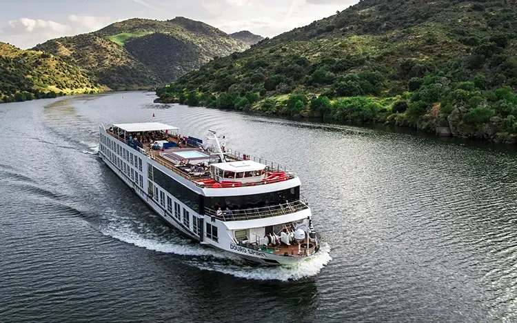 Flusskreuzfahrtschiff fährt durch eine kurvenreiche Flusslandschaft mit grünen Hügeln entlang des Douro.