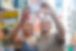 Städtetrip New York – Selfie am Times Square Zwei Personen machen ein Selfie am Times Square in New York zwischen Leuchtreklamen