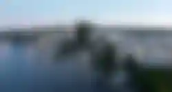 Moderne Brücke über einem Fluss in tropischer Umgebung mit Palmen bei Sonnenuntergang in Thailand.