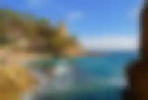 Klippenlandschaft mit küstennahen Gebäuden und Wellen an der Costa Brava in Spanien.