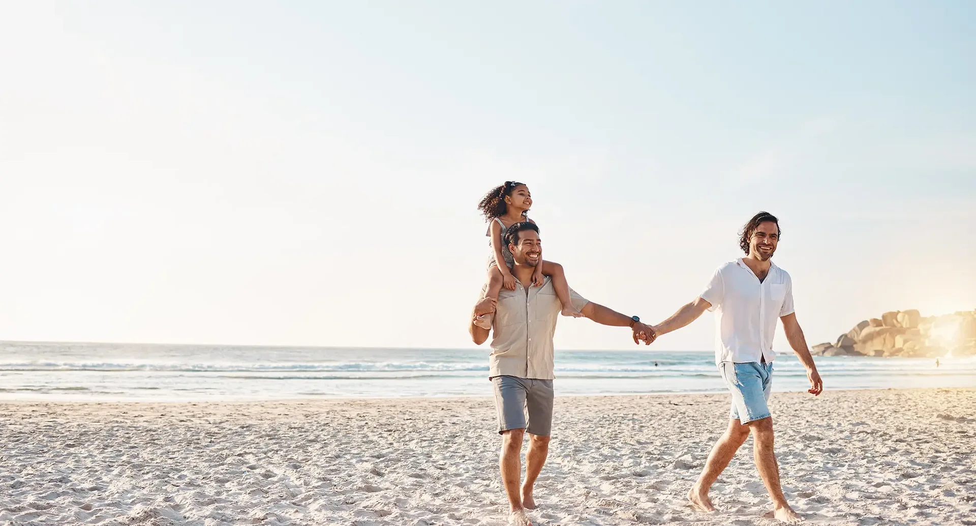 Drei Personen verbringen gemeinsam Zeit an einem Sandstrand am Meer während eines entspannten Urlaubs