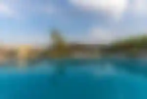 Großer Hotelpool mit Palmen, Liegen und moderner Resortanlage im Hintergrund bei ruhiger Abendstimmung an der türkischen Mittelmeerküste.