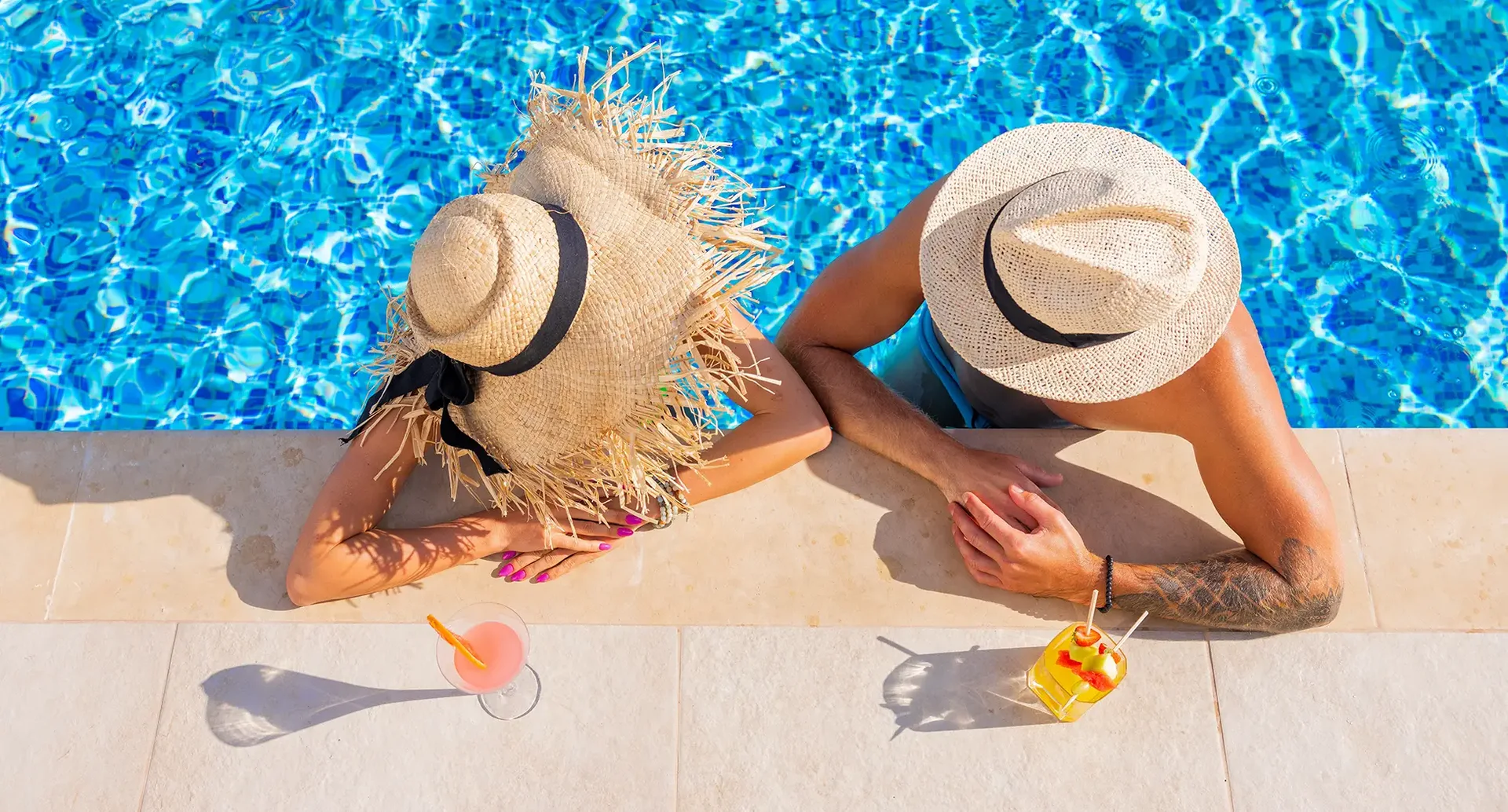 Entspannung am Pool während des Türkeiurlaubs : Zwei Personen mit Sonnenhüten entspannen am Pool mit Getränken