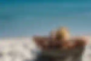 Entspannende Person liegt auf einem Strandstuhl am Sandstrand und blickt auf das ruhige, türkisfarbene Meer in Antalya.