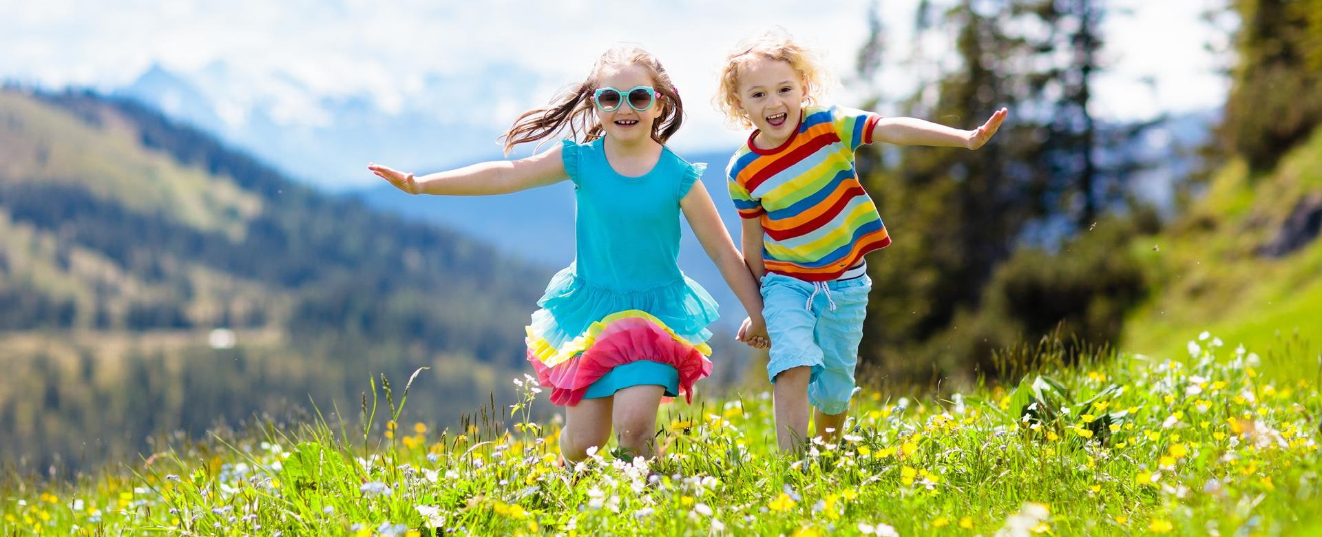 Kinder laufen ueber Almwiese