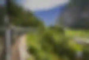 Zug der Flåmbahn auf kurviger Strecke durch grüne Täler, Berge und norwegische Landschaft
