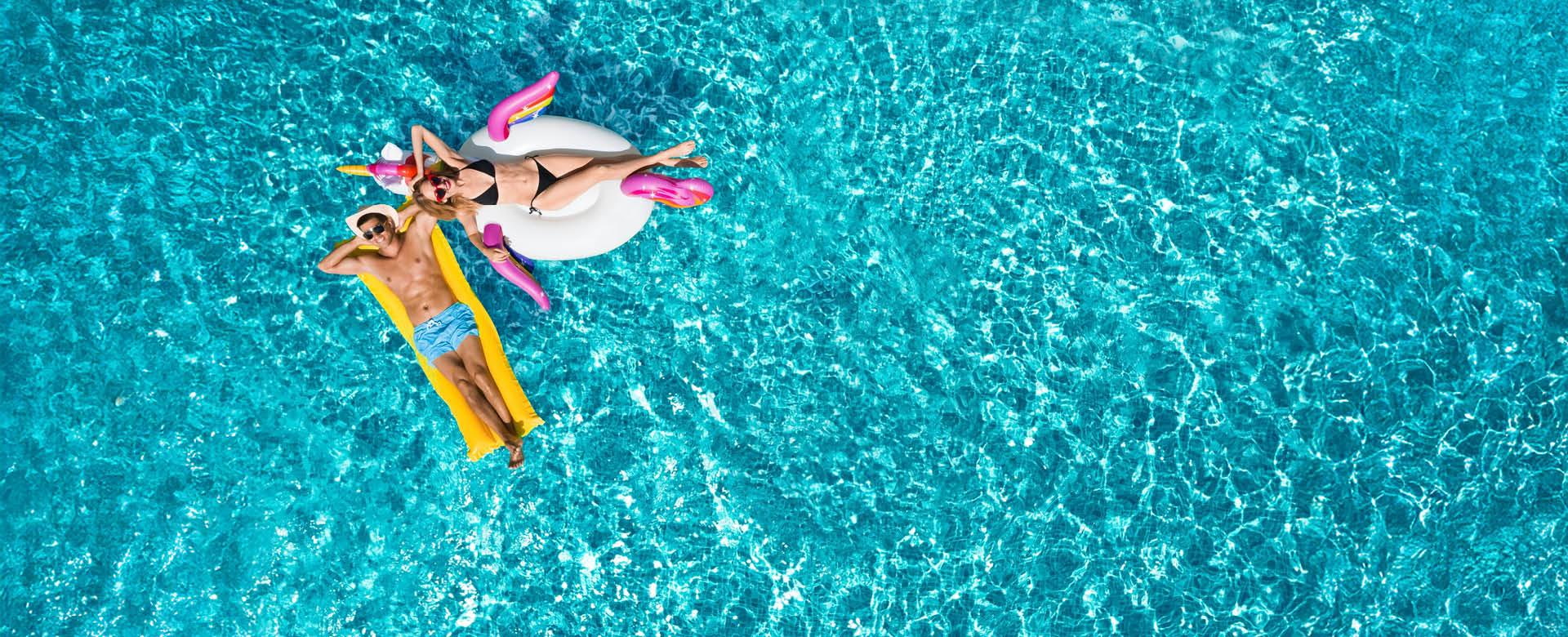 Entspannter Badeurlaub im Meer – perfekte Vorbereitung mit Packliste Personen entspannen auf Luftmatratzen im türkisblauen Meer im Sommerurlaub