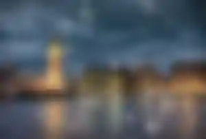 Big Ben und das Parlamentsgebäude in London bei Schneefall am Abend, mit Spiegelungen auf der Themse und winterlicher Atmosphäre.