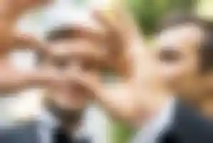 Zwei Personen halten Eheringe vor der Kamera während einer Hochzeitszeremonie