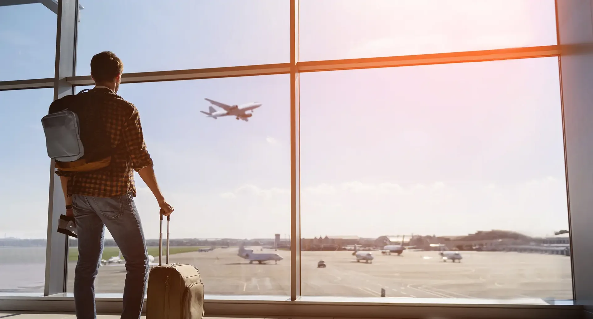 Mann steht am Fenster am Flughafen und schaut auf Flugzeuge