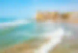 Küstenpromenade und Sandstrand von Sitges mit türkisblauem Meer und historischer Altstadt