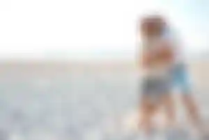 Zwei Personen spazieren gemeinsam über einen Sandstrand auf Mykonos und genießen den Urlaub am Meer
