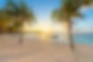 Karibischer Strand in Mexiko mit Palmen, kleinen Booten und ruhigem Meer im Abendlicht